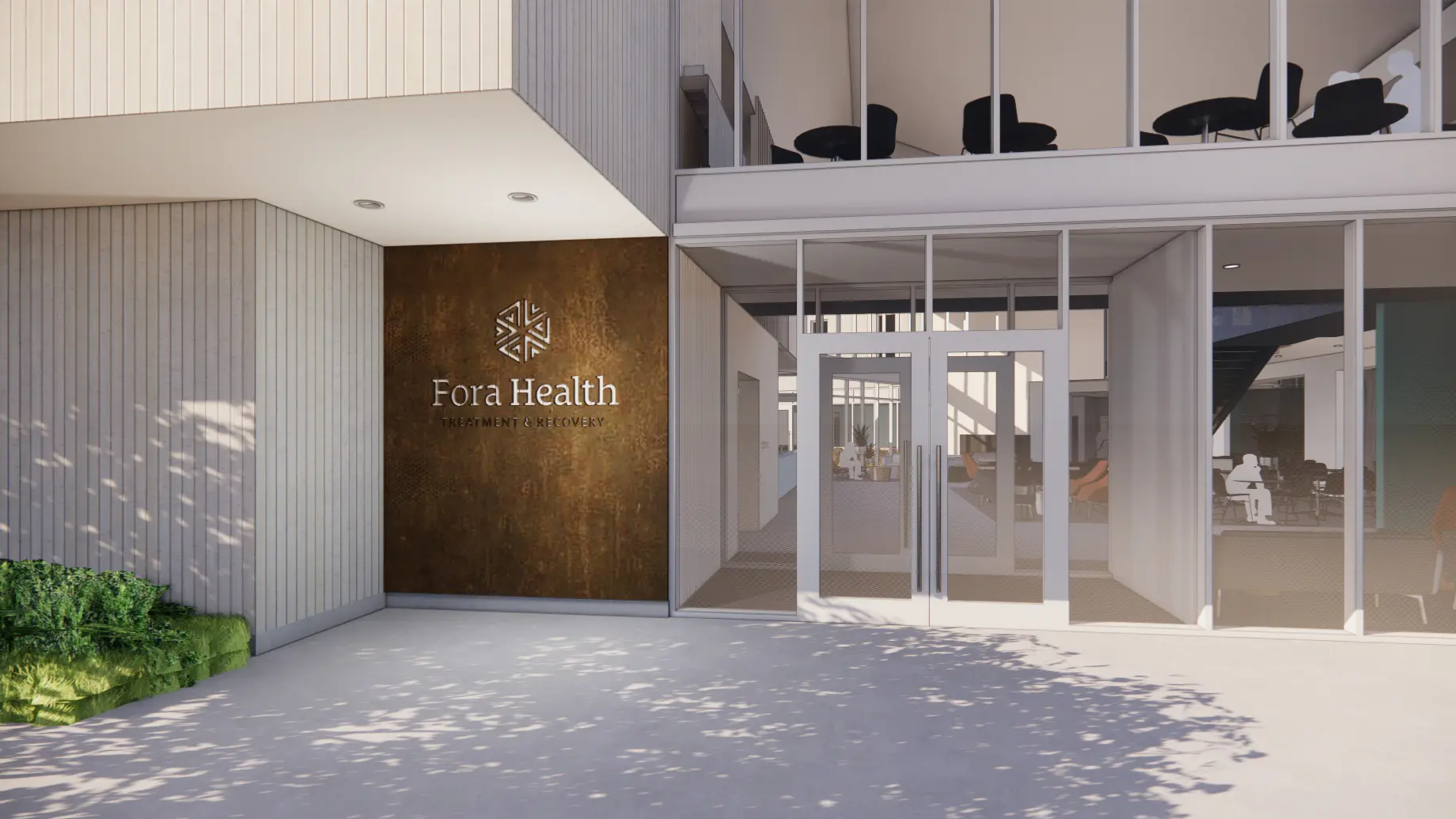 View of entrance to Fora Health. Glass doors and rusted metal wall with logo